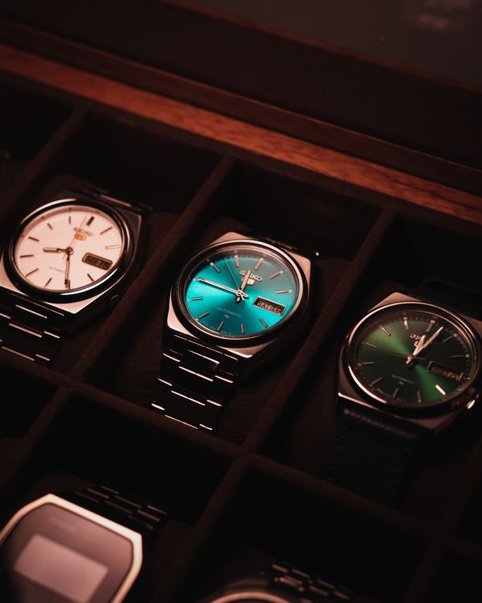 collection-03 Close-up of luxury wristwatches in a display case with vintage style lighting.