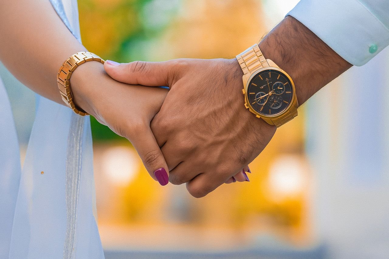 Crafting Captivating Headlines: Your awesome post title goes here A close-up of a couple holding hands, both wearing matching gold watches, symbolizing love and connection.